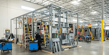 Large industrial automation system with electrical control panels being assembled on a factory floor